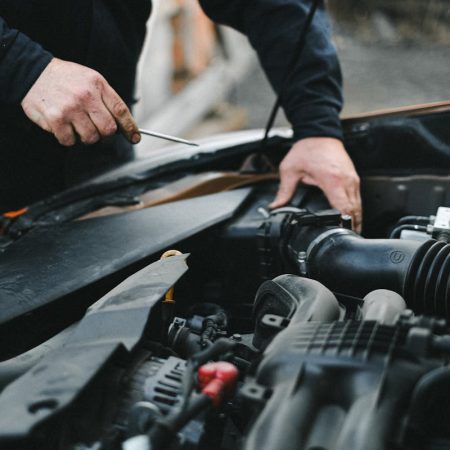 A mechanic working on a car engine with tools, focused on repairs.